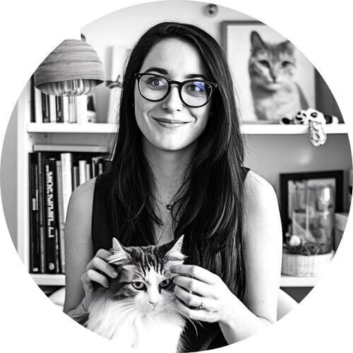 Woman with glasses holding a fluffy cat, smiling at the camera